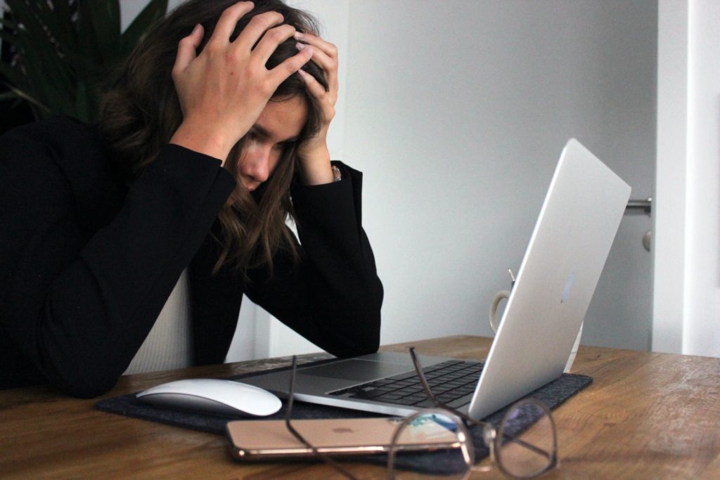 Image that shows a woman frustrated looking at a computer.