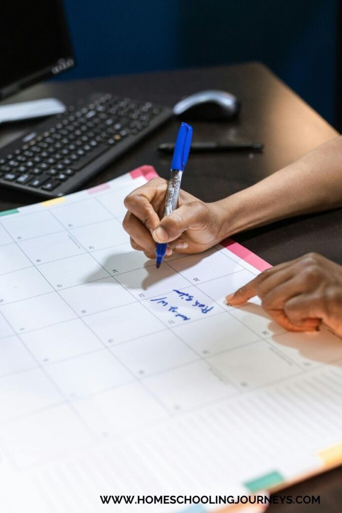 Image of calendar with a person writing homeschool dates. 