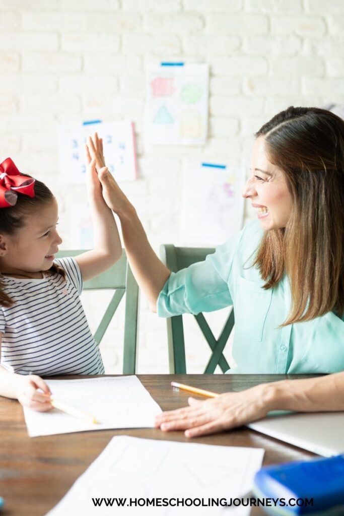 An image of a mother and child completing school work and high fiving each other. 