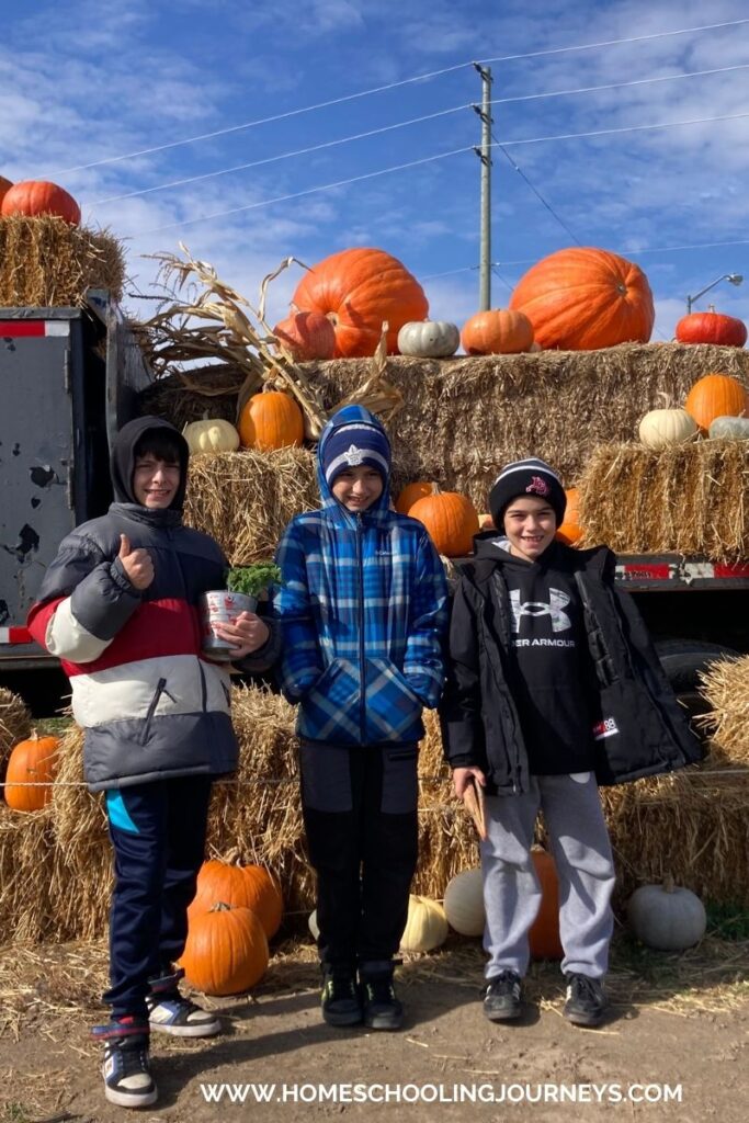 An image of kids at the farm with hay and pumpkins in the background. 