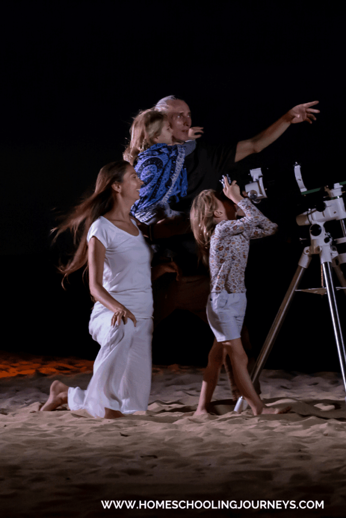 An image of a family stargazing at night through a telescope.  